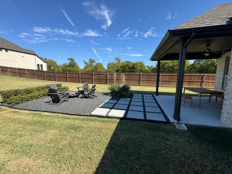 Concrete patio slab extended beyond a covered patio, with square pads and a gravel seating area