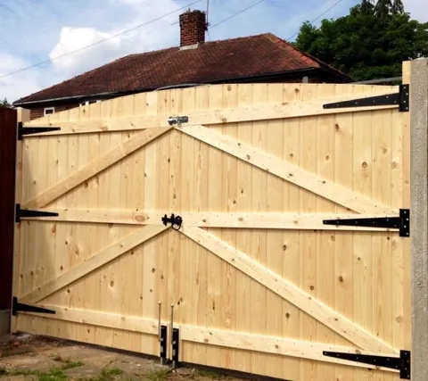 Braced wood double gate with black strap hinges
