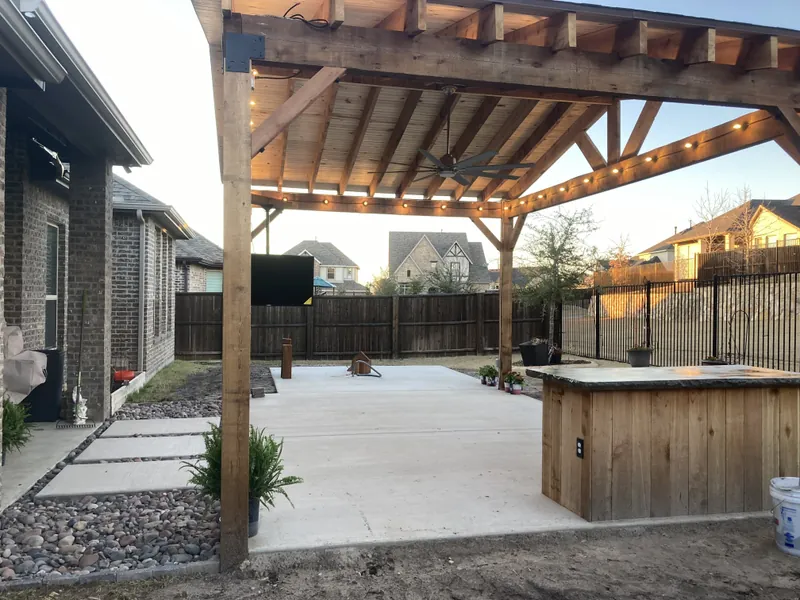 Cedar patio cover with string lights over a large concrete patio and a wood-clad outdoor bar