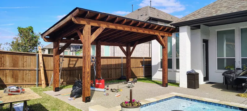 Freestanding cedar pergola over an exposed aggregate patio beside a pool